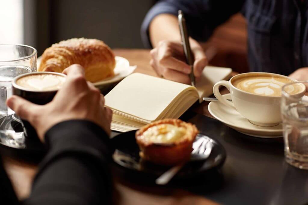 Close Up Of A Woman Writing In A Notebook At A Breakfast Meeting
