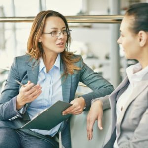 two women talking with clipboard