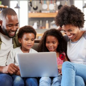 family-sitting-on-sofa-in-open-plan-lounge-using laptop