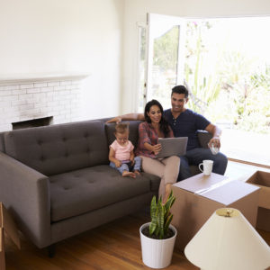 Family Take A Break On Sofa Using Laptop On Moving Day
