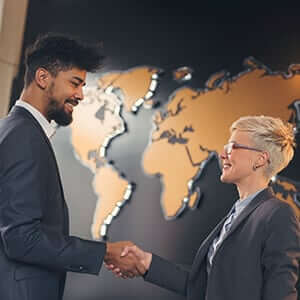 Two business professionals shaking hands with a global map in the background