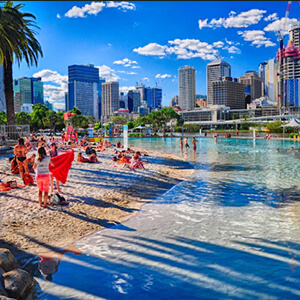 A view of Brisbane’s man-made beach with the skyscrapers of the city centre in the background