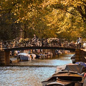 A bridge over one of Amsterdam’s canals with autumn leaves and bicycles lining the paths