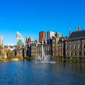 A line of waterfront buildings in the Hague, the Netherlands, with blue skies and green trees