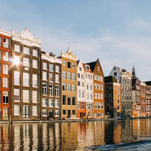 A row of colourful old, terraced houses along a canal in Amsterdam