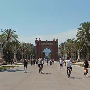 Arc de Triomf in Barcelona between palm-lined streets and people walking and cycling nearby