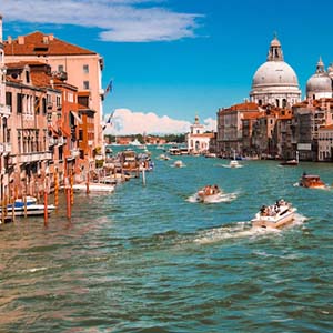 Boats on the waterways of Venice with red-roofed buildings lining the water’s edge