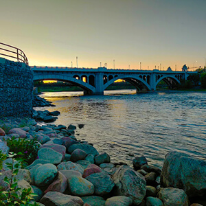 Calgary Centre bridge at a sunset viewed from the riverbank