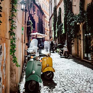 Shot of a cobbled narrow street in Rome with two Vespa scooters standing on the stones