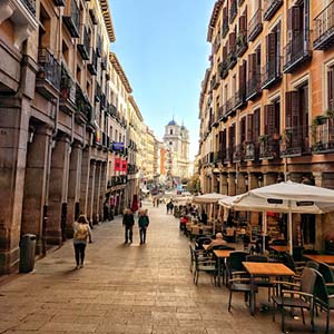 Tables and chairs and people walking through the Plaza Mayor in Madrid city