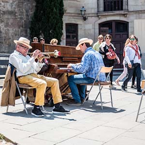 Two musicians playing the trumpet and piano in Barcelona with tourists passing by
