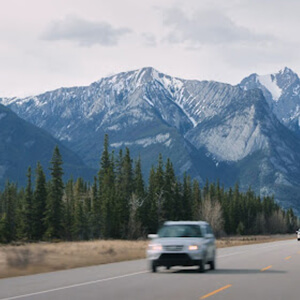 Vehicles driving on open Canadian roads with mountains in the background