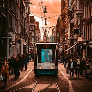 View of an Amsterdam tram in a crowded cobbled street with tall buildings and shops