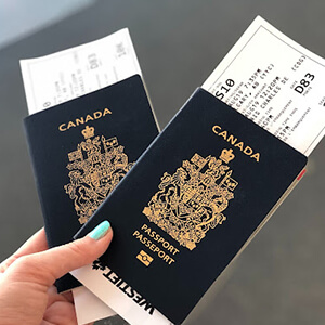 Woman’s hand holding two Canadian passports and airline tickets