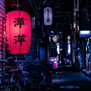 A lit-up street at night with shops and bicycles lining the buildings in Kyoto, Japan