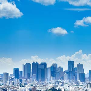 Tokyo’s skyline of high-rise buildings against a blue sky with some small clouds