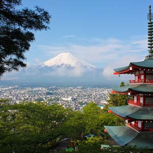 View across a city to snowy mountain Fuji, Japan, with a Pagoda temple in the foreground
