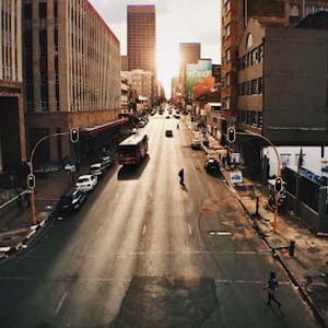 View down a wide main road in Johannesburg with passing cars and people