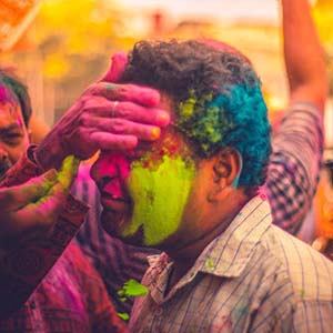 A man being covered in colourful dust as part of the Holi festival in India