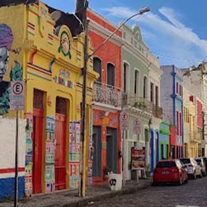 A street with colourful buildings in Recife, Brazil, with parked cars lining the street