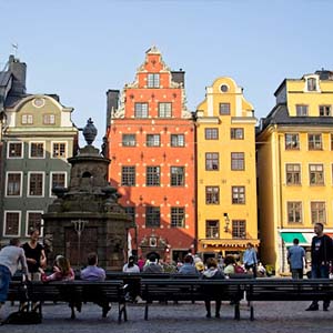 People sitting on benches in a square in Stockholm, Sweden surrounded by colourful old buildings