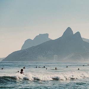 People surfing at the beach in Rio de Janeiro, Brazil with mountains in the background