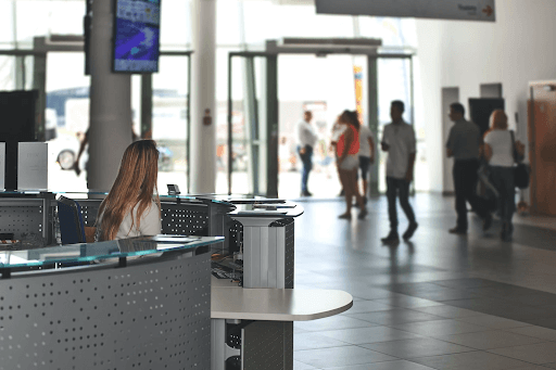 Woman sitting behind a desk with business people walking around the ground floor.