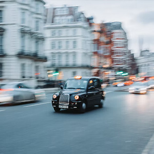 Black taxi cab driving through the streets of London, UK