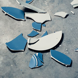 Blue ceramic item smashed into pieces on the floor