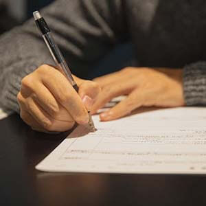 Man filling in a paper form on a desk