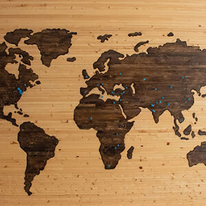 Map of the world on a wooden wall with blue pins