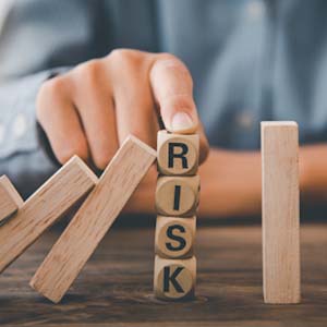 Wooden blocks knocking each other over being stopped by blocks that say RISK