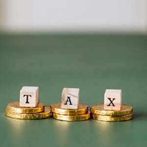 Wooden blocks with letters spelling tax placed on gold coins