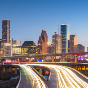 Sunset road leading to Houston, Texas, with bright lights from headlights