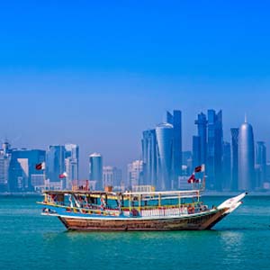 Heat haze over the skyline of Doha with a traditional wooden boat anchored in front