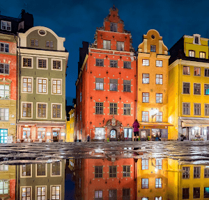 Colourful houses at Stortorget town square in Stockholm’s Gamla Stan (Old Town) reflected in a puddle at night