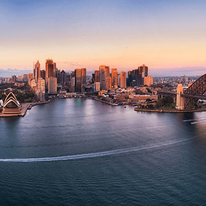 Panoramic view of Sydney’s skyline at sunrise featuring Sydney Harbour, Sydney Harbour Bridge, and Sydney Opera House