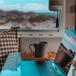 A laptop inside a campervan by a beach