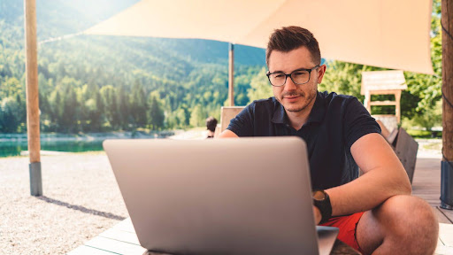 A Man Working On A Laptop On A Beach