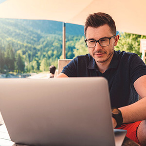 A man working on a laptop on a beach