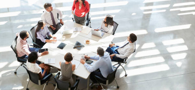 Group Of Employees Sitting Around An Office Table
